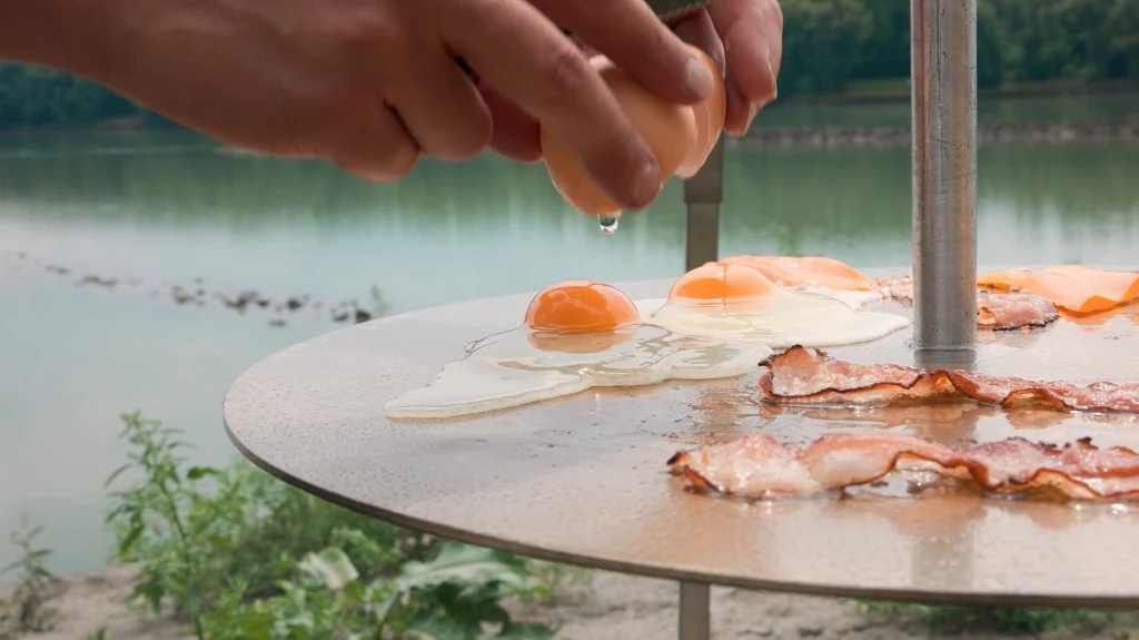 Eier und Speck auf der Edelstahl-Grillplatte am Wasser