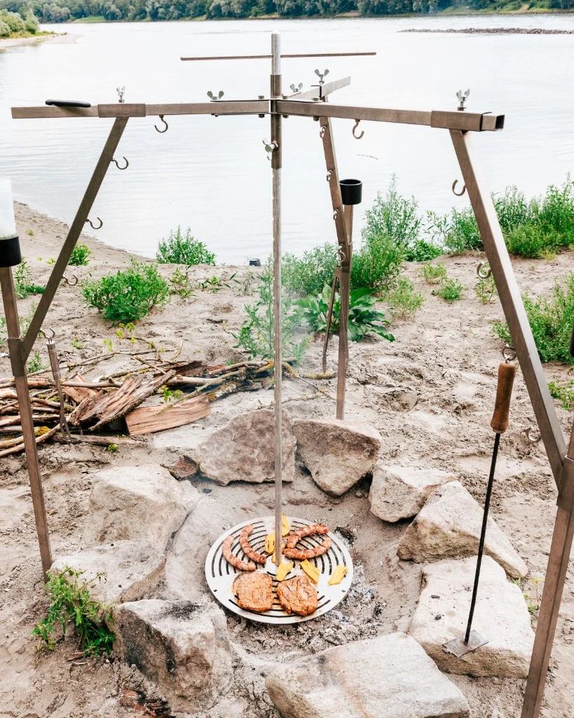 Grillrost im Einsatz am Flussufer mit Würstchen und Steaks